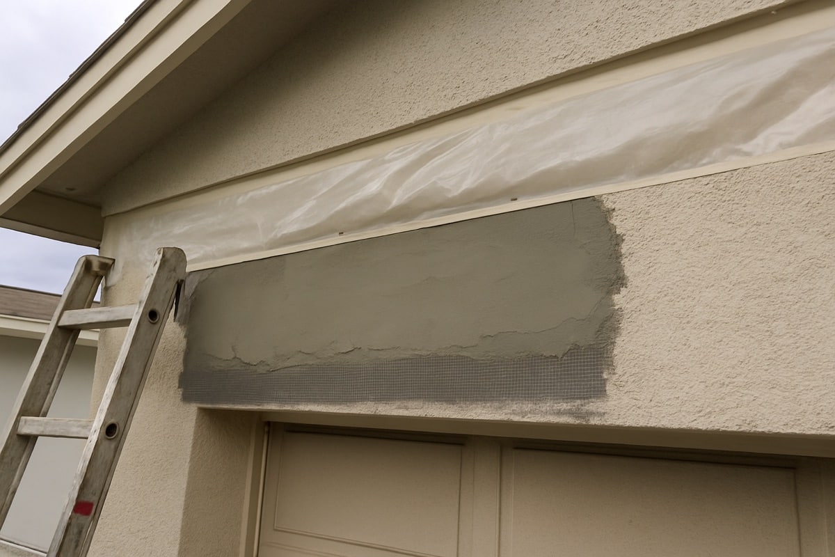 Freshly repaired stucco band section at an eave with new mesh and base coat curing